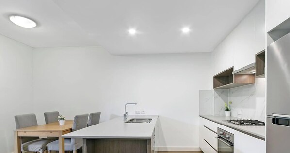 A modern kitchen with a central island, a dining table with chairs, and built-in appliances.