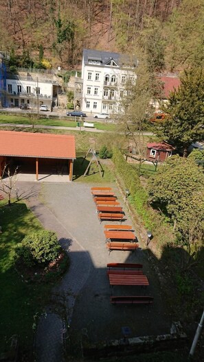 A row of wooden benches in a park area with a building in the background. - Kurparkstübl Bad Schandau (Bad Schandau)