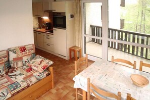 Enjoy a meal for two in this inviting room, featuring a dining area, kitchenette, and balcony with a wooded view.
