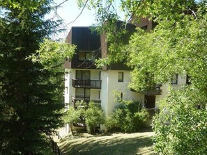 A two-story building with a balcony on the second floor, surrounded by greenery. - 50m from ski slopes, 3rd floor, balcony, 30m², Les Orres (Les Orres)