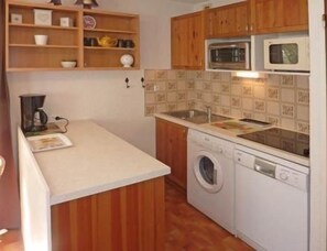 A compact kitchen with wooden cabinets, a washing machine, a microwave, and a coffee maker. - 50m from ski slopes, 3rd floor, balcony, 30m², Les Orres (Les Orres)