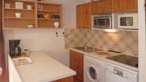 A compact kitchen with wooden cabinets, a washing machine, a microwave, and a coffee maker. - 50m from ski slopes, 3rd floor, balcony, 30m², Les Orres (Les Orres)