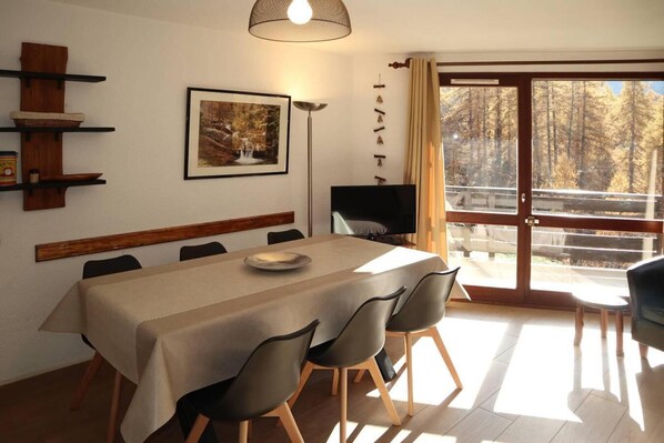 A dining area with a table, chairs, a framed picture, and a TV.