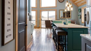 Una cocina moderna con una isla central, suelo de madera y ventanas amplias.