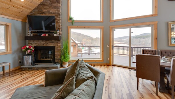 Una sala de estar acogedora con chimenea, ventanas amplias y un comedor.