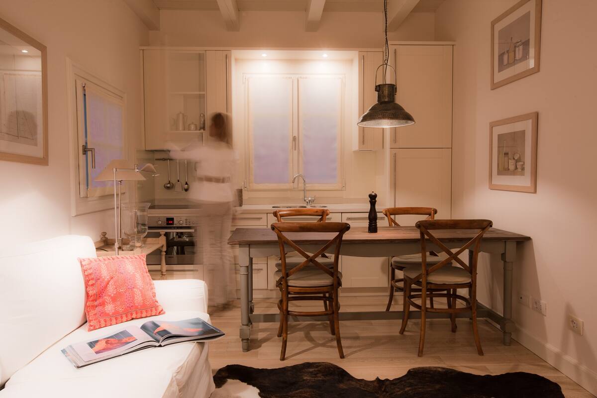 Una cocina funcional con sillas de madera, una encimera blanca y una lámpara colgante.