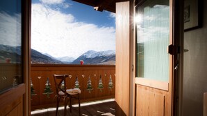 A wooden deck with a chair and a red cup, overlooking snow-capped mountains. - Les Fleurs Bleues chalets (Livigno)