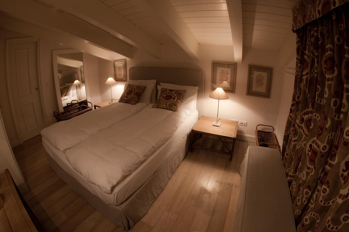 Un dormitorio con una cama grande, mesitas de noche, un espejo y una lámpara.