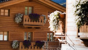 A wooden chalet with balconies adorned with flower boxes and decorative cutouts. - Les Fleurs Bleues chalets (Livigno)