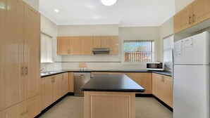 Une cuisine moderne avec des meubles en bois, un îlot central, un lave-vaisselle, un four à micro-ondes et un réfrigérateur.