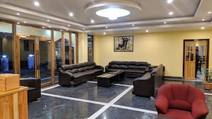 Un hall d’entrée spacieux, avec un grand canapé d’angle, un fauteuil rouge et une table basse.