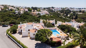 Zona residencial con piscina, edificios blancos y abundante vegetación.
