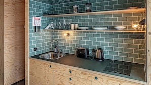 Una cocina con armarios de madera, salpicadero de azulejos verdes y electrodomésticos de acero inoxidable.