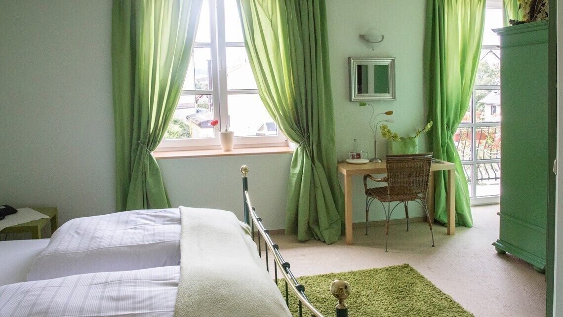 A bedroom with two beds, a desk, and a chair.