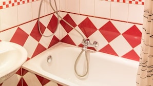 A bathroom with a white bathtub, a white sink, and a shower with a hose. - Villa ZOE St Wendel (Sankt Wendel)