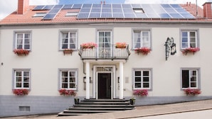 A building with solar panels on the roof, a white facade, and multiple windows with flower boxes. - Villa ZOE St Wendel (Sankt Wendel)