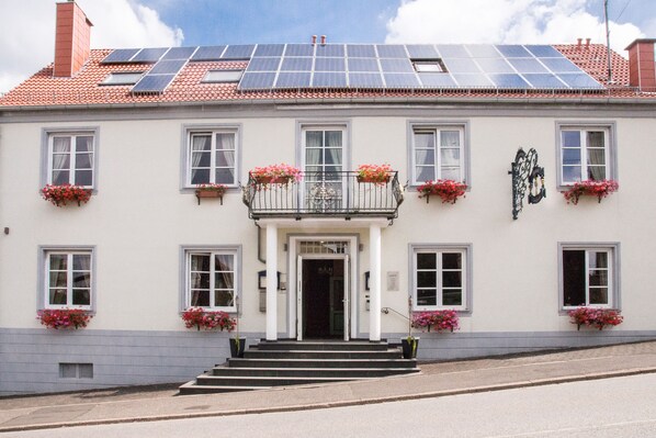 A building with solar panels on the roof, a white facade, and multiple windows with flower boxes. - Villa ZOE St Wendel (Sankt Wendel)