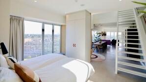 Ein modernes Hotelzimmer mit einem großen Bett, einem Essbereich und einer Treppe.