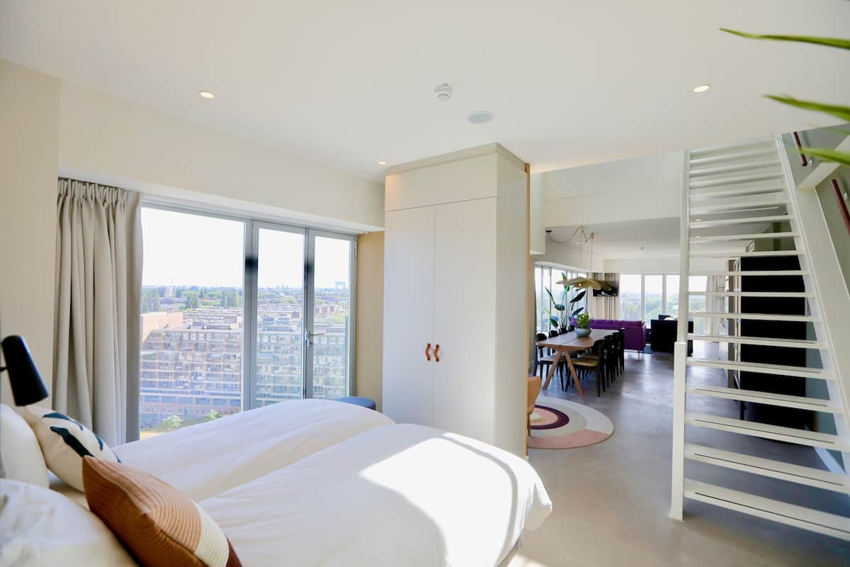 Una habitación de hotel moderna con una cama grande, un área de comedor y una escalera.