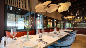 Ein Restaurant mit einem langen Tisch, gedeckt für ein Essen, mit weißen Tellern, Gläsern und Besteck.