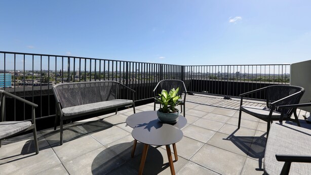 Eine Terrasse mit Blick auf die Stadt, ausgestattet mit einem Tisch, Stühlen und einem Blumentopf.