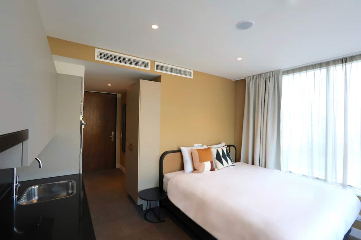 Una habitación de hotel con una cama, un lavamanos y una puerta que da a otra habitación.