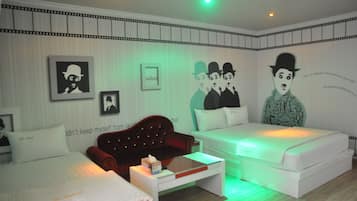 A hotel room with a bed, a red sofa, a white bedside table, and a small table with a box.