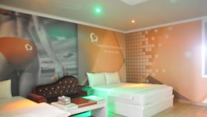 A modern hotel room with a bed, a sofa, and a small table. There is a wall with a heart-shaped design and a quote. - W Motel (Andong)