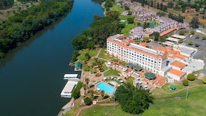 An aerial view of a hotel with a swimming pool, a dock, and a large building with multiple balconies. - Riviera On Vaal Resort (Vereeniging)