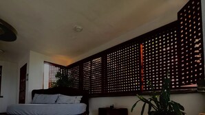 Un dormitorio con una cama, una mesa de madera y una planta en maceta.