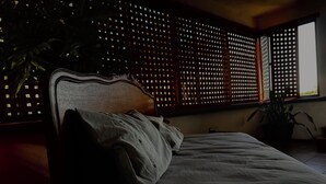 Una cama con cabecera, una ventana con vistas y una planta.