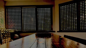 Una mesa de madera con una bandeja metálica en el centro, frente a una pared con dos ventanas de diseño calado.