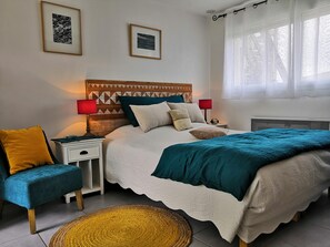 A neatly arranged bedroom with a bed, two bedside tables, a chair, and a window with curtains. - Cottage Maison Drogou (Porspoder)