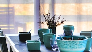 A dining table with teal-colored bowls and a potted plant. - Cottage Maison Drogou (Porspoder)