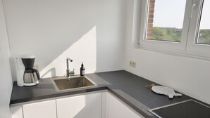 A modern kitchen with white cabinets, a black countertop, a built-in oven, and a window with a view of greenery.