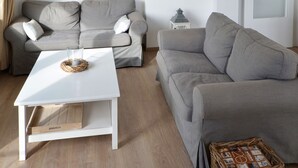 A modern living room with a grey sofa, a white coffee table, and a wicker basket.