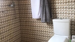 A bathroom with a patterned wall, a toilet, a shower, and a green cleaning brush. - Rainbow Aparts (Kigali)