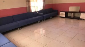 A waiting area with a blue sofa, a small table, and a cabinet. - Rainbow Aparts (Kigali)