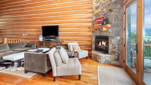 A cozy log cabin interior with a stone fireplace, wooden walls, and a comfortable seating area. - Beautiful Ski-In/Ski-Out Log Townhome with Exceptional Views (Mountain Village)