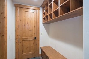 A wooden door with a handle, a bench, and a wooden shelving unit against a white wall. - Townhomes on the Creek 117 (Mountain Village)