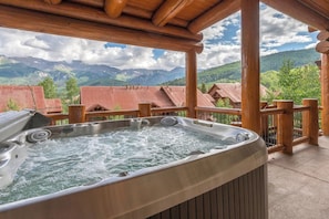 Un bain à remous sur une terrasse en bois avec vue sur les montagnes.
