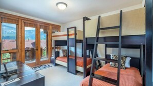 Habitación con literas, un escritorio, vistas al exterior y una puerta que da a un espacio exterior.
