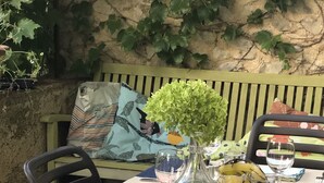 Una mesa de comedor decorada con cristalería, un florero con follaje verde y una vela en un tarro.