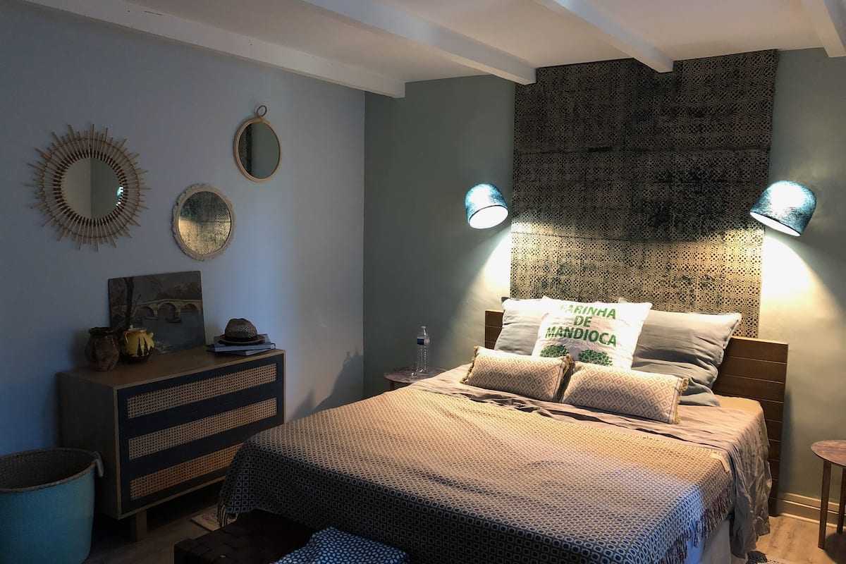 Een slaapkamer met een bed, bedlampen, een kaptafel, een spiegel en een bed hoofddeksel met patroon.