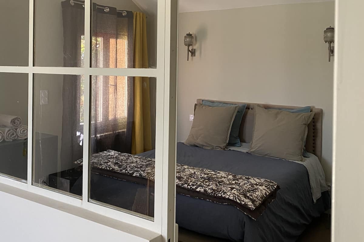 Een slaapkamer met een bed, gordijnen en een wandlamp.