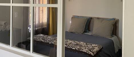 A bedroom with a bed, curtains, and a wall-mounted light fixture.