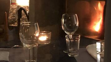 Een tafel met kaarsen en glazen, een kandelaars en een plantje op de achtergrond.