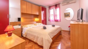 Une chambre bien rangée, avec un lit, une table de chevet, une lampe, une armoire et un téléviseur.
