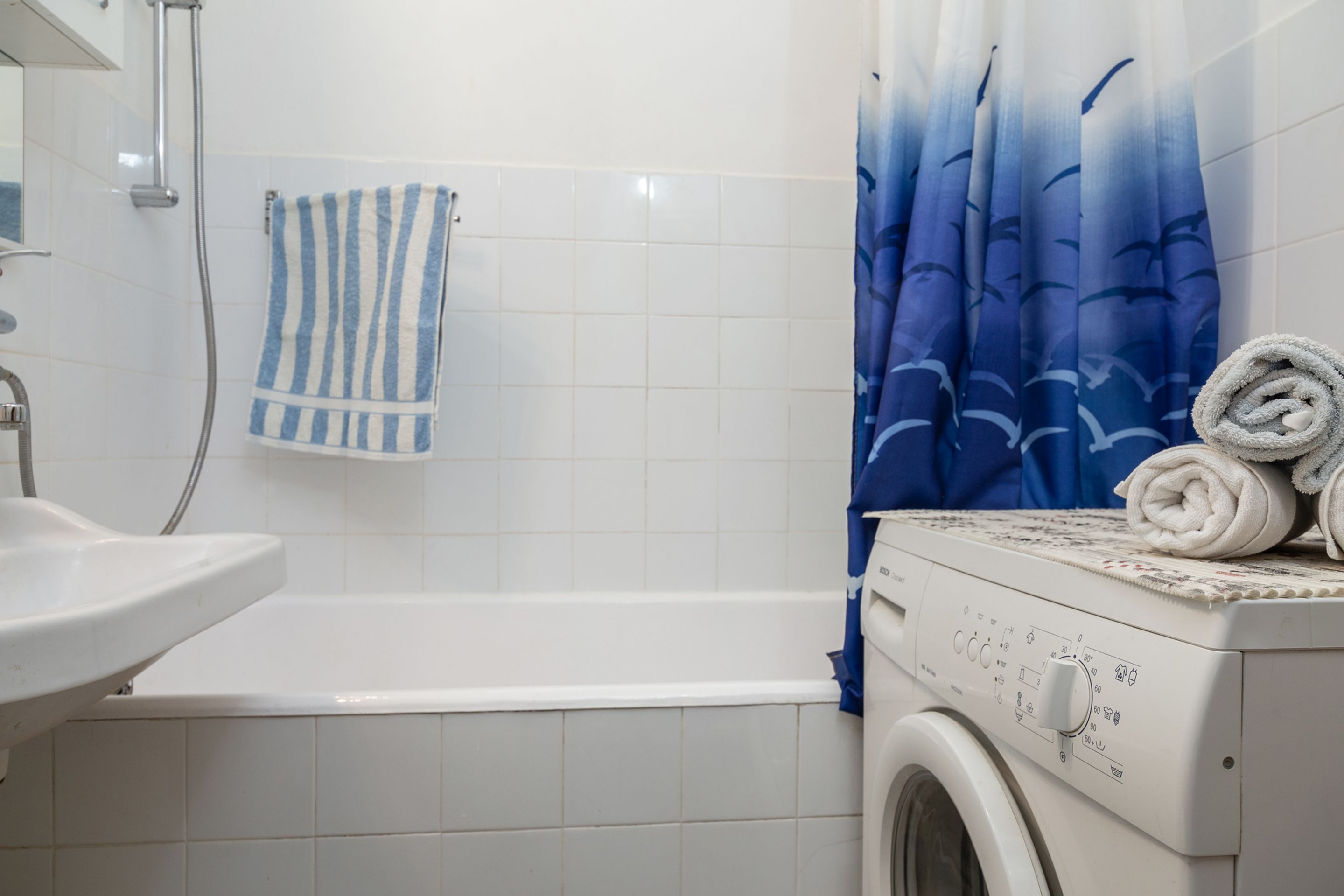 A bathroom with a white sink, a bathtub, and a washing machine.