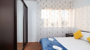 A hotel room with a bed, a nightstand, a mirror, and a window with sheer curtains. - Apartment Anica (Split)